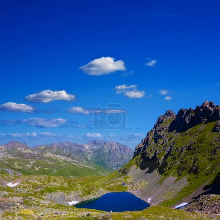 small blue lake among green mountain valley