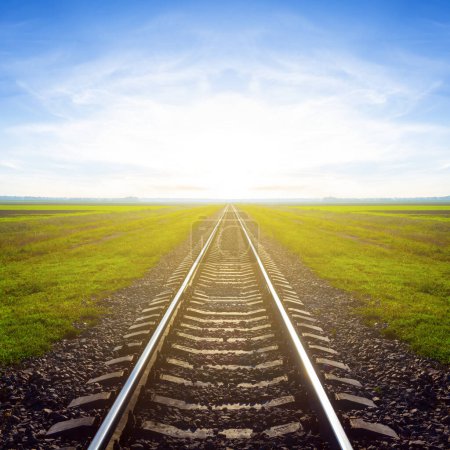 chemin de fer parmi la plaine verte au lever du soleil