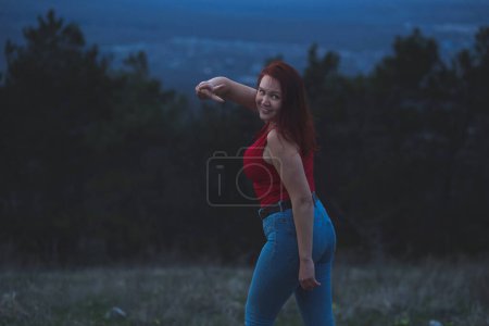 Téléchargez les photos : Jeune femme courbée posant dans les montagnes du crépuscule. Une soirée paisible. Détendez-vous, solitude - en image libre de droit