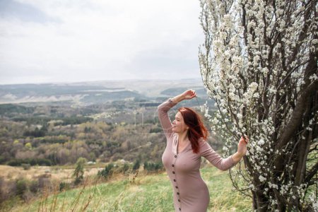 Téléchargez les photos : Belle femme courbée parmi les arbres en fleurs dans les collines - en image libre de droit
