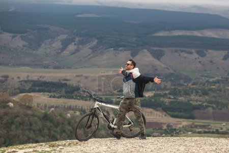 Foto de Un hombre feliz subió a la montaña en bicicleta y se regocija en la victoria - Imagen libre de derechos