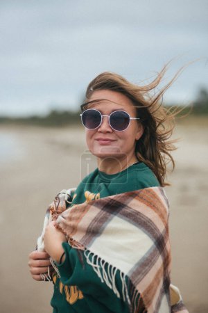 Photo for Smiling girl in sunglasses against a stormy sea. Film grain. High quality photo - Royalty Free Image