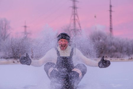 Téléchargez les photos : Un homme joyeux et courageux en vêtements noirs qui s'amuse sur la neige blanche en hiver et crie de bonheur et d'émotion. Photographie, concept. Photo de haute qualité. - en image libre de droit