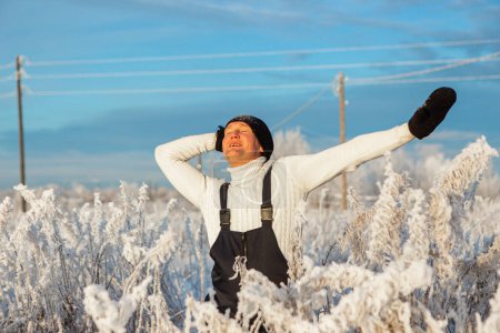 Téléchargez les photos : Un homme joyeux et courageux en vêtements noirs qui s'amuse sur la neige blanche en hiver et crie de bonheur et d'émotion. Photographie, concept. Photo de haute qualité. - en image libre de droit