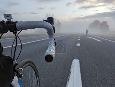 Téléchargez les photos : Vélo de route sur l'autoroute avant une course longue distance par un matin brumeux. Photo de haute qualité - en image libre de droit