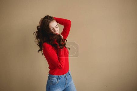 Téléchargez les photos : Gros plan jeune femme séduisante 20s au col roulé rouge isolé sur fond beige pastel uni studio. Concept de style de vie - en image libre de droit