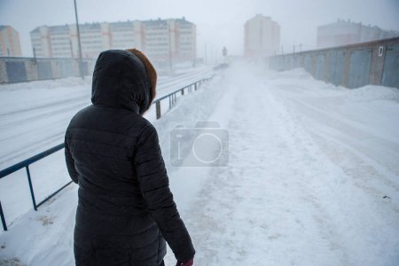 Photo for Winter is coming by severe blizzard. Poor visibility in heavy snow storm on path. Woman slowly and hard walking in dangerous weather day. Cataclysm of nature. City people life in blizzard concept - Royalty Free Image