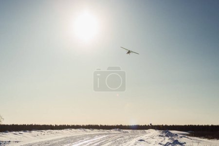 Téléchargez les photos : Avion ultra-léger à hélice unique avec skis survolant le ciel bleu en hiver - en image libre de droit