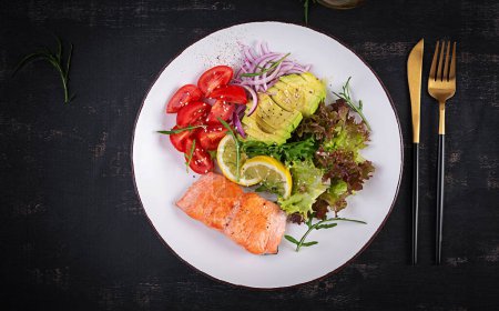 Photo for Ketogenic diet breakfast. Baked salmon salad with greens, tomatoes, red onions and avocado. Keto, paleo lunch. Top view, overhead - Royalty Free Image