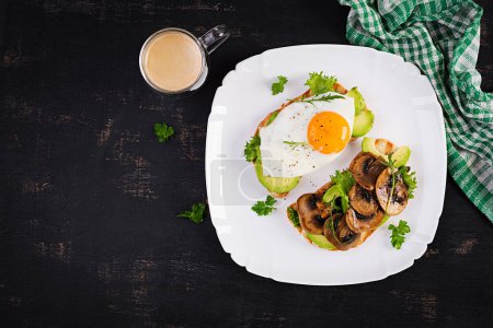 Foto de Sandwiches  with avocado, fried egg and mushrooms  for healthy breakfast or snack. Top view, above - Imagen libre de derechos