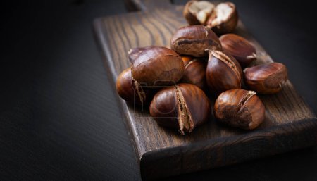 Foto de Roasted chestnuts on dark wooden background - Imagen libre de derechos
