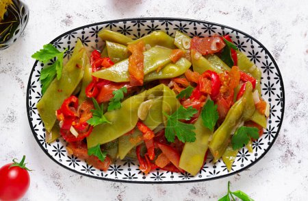 Foto de Homemade stewed green beans, tomatoes, garlic with olive oil. Zeytinyagli fasulye traditional food. Turkish cuisine. Top view, flat lay - Imagen libre de derechos