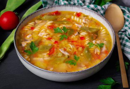 Téléchargez les photos : Minestrone, italian vegetable soup with pasta on black table. - en image libre de droit