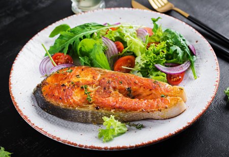 Foto de Roasted salmon garnished with fresh salad. Ketogenic lunch. Keto diet. - Imagen libre de derechos