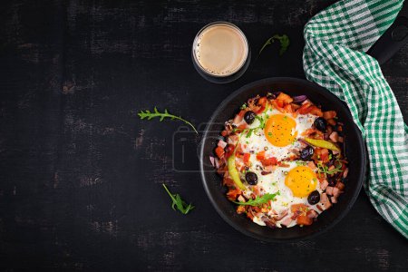 Téléchargez les photos : Fried eggs with vegetables on pan - pepperoni, tomatoes, ham, onion and black olives. Ketogenic breakfast. Top view, above - en image libre de droit