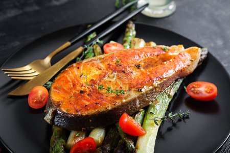 Foto de Roasted salmon garnished with asparagus and tomatoes with herbs. Ketogenic lunch. Keto diet - Imagen libre de derechos