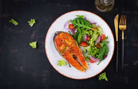 Téléchargez les photos : Roasted salmon garnished with fresh salad. Ketogenic lunch. Keto diet. Top view, above - en image libre de droit