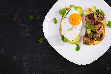 Foto de Sandwiches  with avocado, fried egg and mushrooms  for healthy breakfast or snack. Top view, above - Imagen libre de derechos