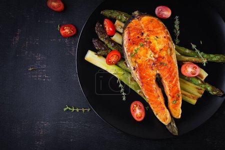 Photo for Roasted salmon garnished with asparagus and tomatoes with herbs. Ketogenic lunch. Keto diet. Top view, above - Royalty Free Image