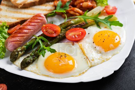 Photo for Keto breakfast. Breakfast. Fried eggs, bread toast, green asparagus, beans and sausage on white plate. - Royalty Free Image