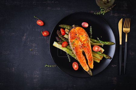 Photo for Roasted salmon garnished with asparagus and tomatoes with herbs. Ketogenic lunch. Keto diet. Top view, above - Royalty Free Image