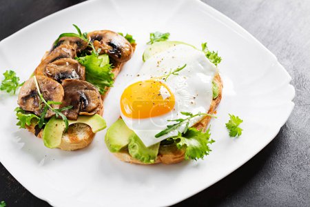 Foto de Sandwiches  with avocado, fried egg and mushrooms  for healthy breakfast or snack. - Imagen libre de derechos