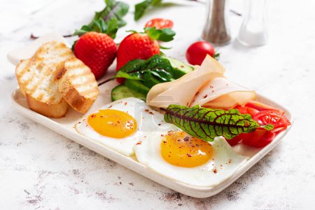 Photo for Fried eggs with ham, tomatoes, cucumber, strawberries and toasts. Delicious English Breakfast. Brunch. - Royalty Free Image