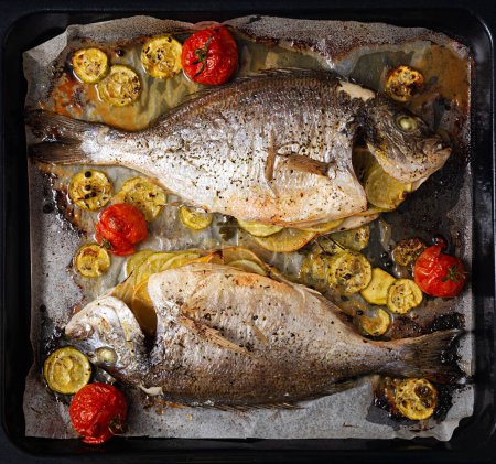 Photo for Baked dorado fish with vegetables on baking sheet. Top view, above - Royalty Free Image