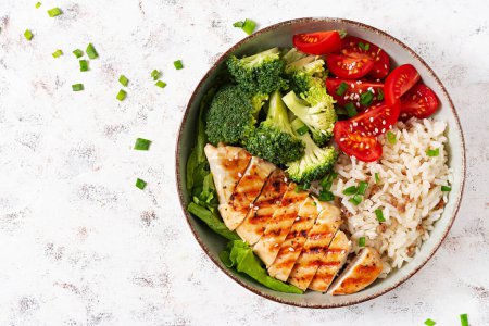 Foto de Delicious buddha bowl with grilled chicken, fresh vegetables and rice on a light background. Top view, above - Imagen libre de derechos