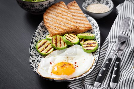 Téléchargez les photos : Breakfast. Toast with avocado guacamole, grilled zucchini and fried egg.  Brunch. - en image libre de droit