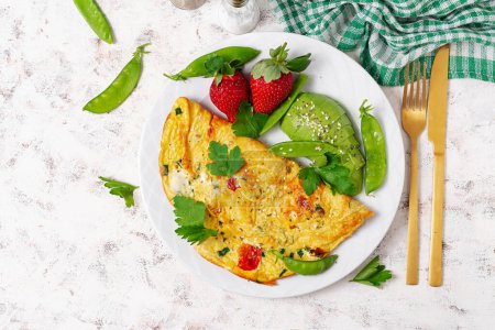 Photo for Omelette with tomatoes, feta cheese and avocado on white plate. Top view, flat lay - Royalty Free Image