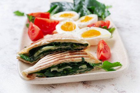 Foto de Tortilla fresca envuelve con espinacas y queso sobre fondo claro. Concepto de comida saludable. Comida vegetariana. - Imagen libre de derechos