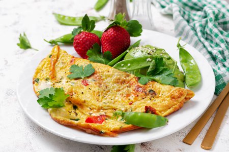 Foto de Omelette with tomatoes, feta cheese and avocado on white plate. - Imagen libre de derechos