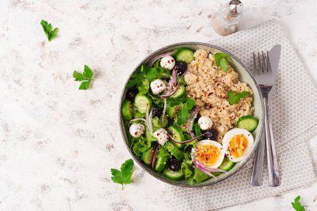 Photo for Breakfast oatmeal porridge with boiled eggs, cucumber, mozzarella cheese and green herbs. Healthy balanced food. Top view - Royalty Free Image