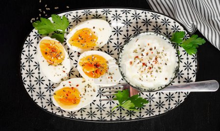 Foto de Boiled eggs with yogurt, peppers, parsley and cup tea. Healthy diet food for breakfast. Top view, flat lay. - Imagen libre de derechos