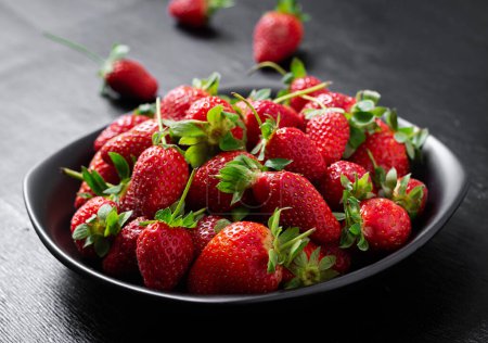 Photo for Strawberries in a black plate on dark background. - Royalty Free Image