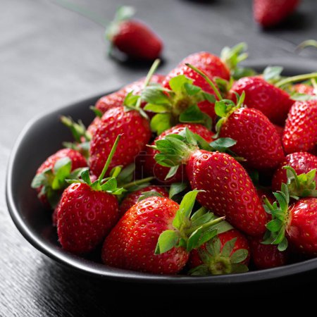 Téléchargez les photos : Strawberries in a black plate on dark background. - en image libre de droit