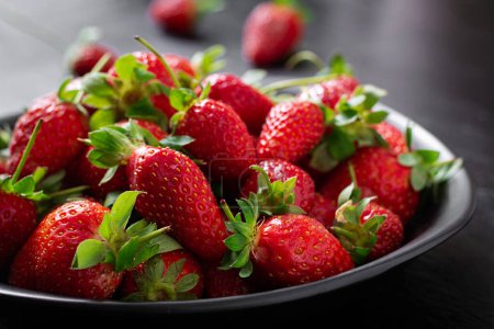 Photo for Strawberries in a black plate on dark background. - Royalty Free Image