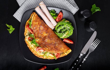 Téléchargez les photos : Petit déjeuner Keto. Tomate à l'omelette, olives et avocat, jambon. Régime cétogène. Faible teneur en glucides petit déjeuner riche en gras. Concept d'alimentation saine. Vue du dessus - en image libre de droit