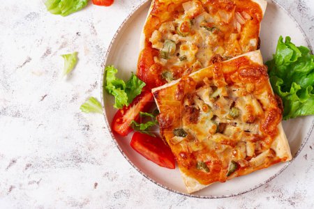 Foto de Mini pizza para niños, pequeños pasteles abiertos con jamón, salsa de tomate, mozzarella y queso en canasta sobre un fondo claro. Vista superior - Imagen libre de derechos