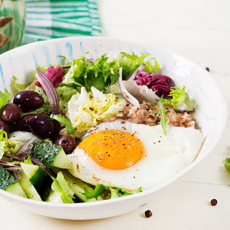 Téléchargez les photos : Petit déjeuner porridge de blé avec oeuf rôti, concombre et olives. Alimentation saine et équilibrée. - en image libre de droit