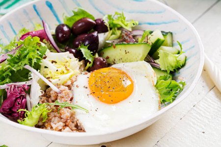 Photo for Breakfast wheat porridge with  roasted egg, cucumber and olives. Healthy balanced food. - Royalty Free Image