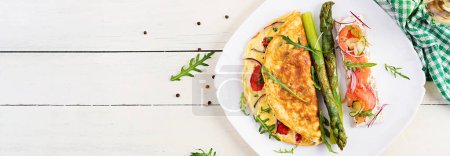 Photo for Ketogenic breakfast. Omelette with tomatoes, red onion, sandwich with salmon and roasted asparagus. Italian frittata. Keto, ketogenic lunch. Top view, banner - Royalty Free Image