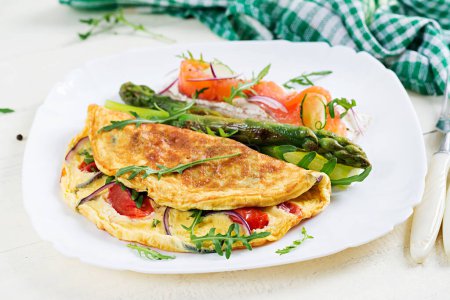 Photo for Ketogenic breakfast. Omelette with tomatoes, red onion, sandwich with salmon and roasted asparagus. Italian frittata. Keto, ketogenic lunch. - Royalty Free Image