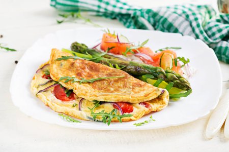 Photo for Ketogenic breakfast. Omelette with tomatoes, red onion, sandwich with salmon and roasted asparagus. Italian frittata. Keto, ketogenic lunch. - Royalty Free Image