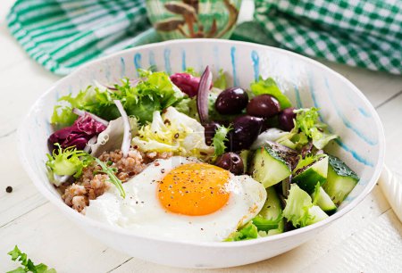Photo for Breakfast wheat porridge with  roasted egg, cucumber and olives. Healthy balanced food. - Royalty Free Image