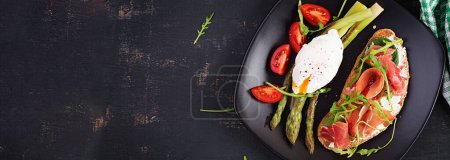 Photo for Keto breakfast. Fried asparagus with poached egg and toast with prosciutto or jamon. Ketogenic diet. Healthy food. Top view, banner - Royalty Free Image