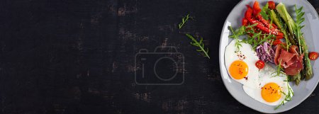 Photo for Keto breakfast. Fried asparagus with roasted eggs and  prosciutto or jamon. Ketogenic diet. Healthy food. Top view, banner - Royalty Free Image
