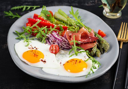 Photo for Keto breakfast. Fried asparagus with roasted eggs and  prosciutto or jamon. Ketogenic diet. Healthy food. - Royalty Free Image