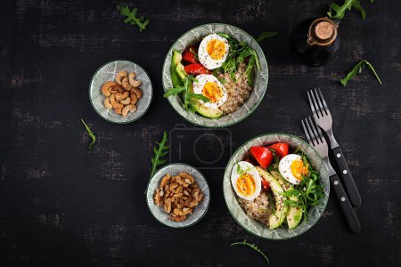 Breakfast oatmeal porridge with boiled eggs, avocado, tomatoes and green herbs. Healthy balanced food. Top view, flat lay